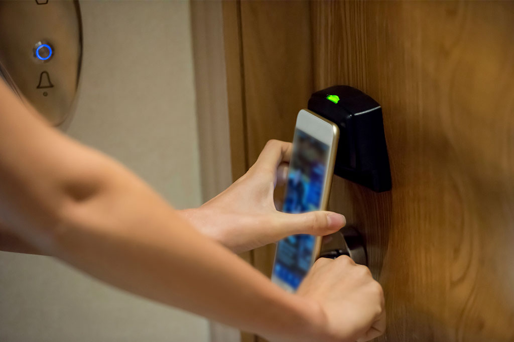 person holding phone to hotel door for keyless entry