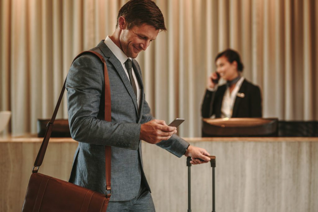 man in hotel lobby looking at smartphone