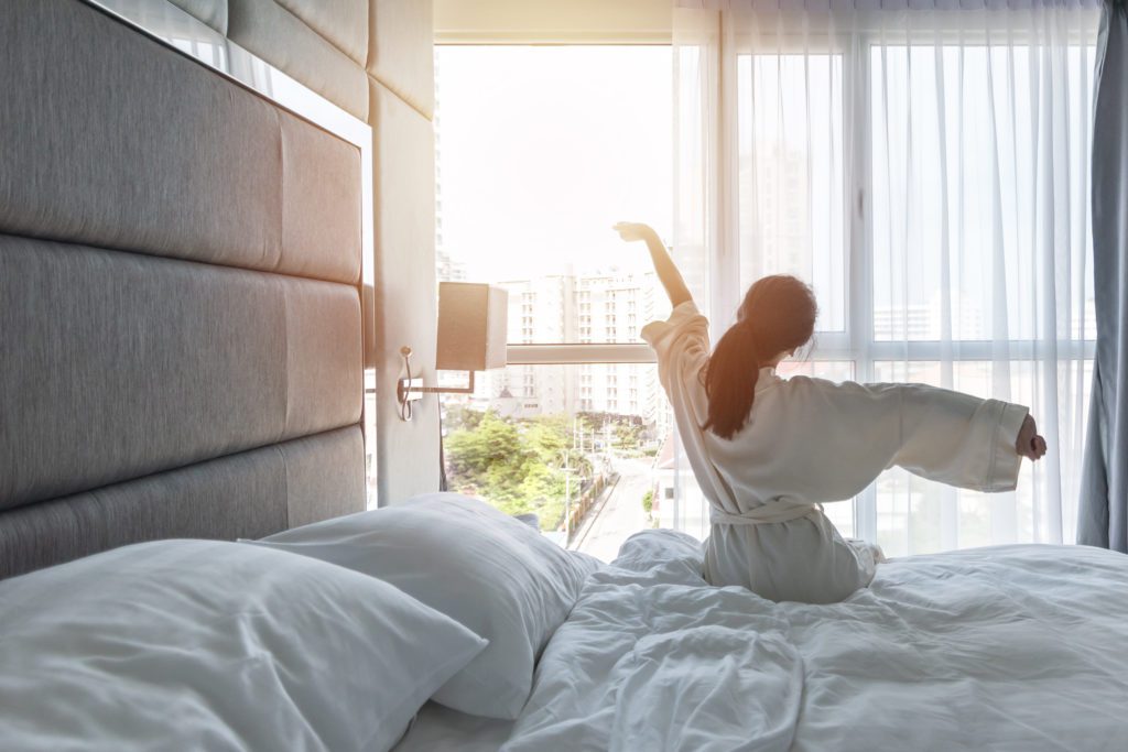 woman waking up and stretching in hotel room